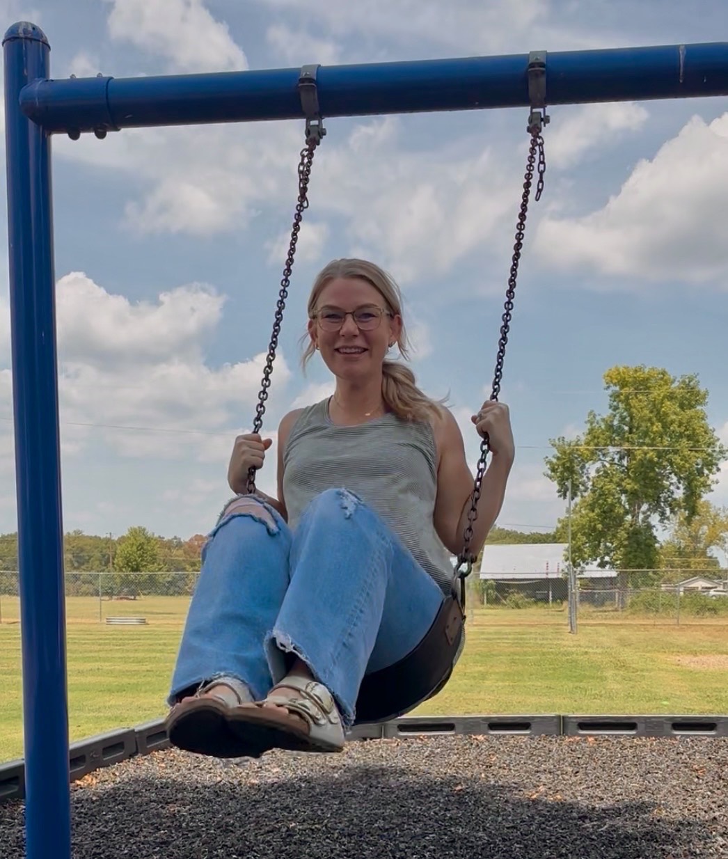 Alexis Gilliam smiling on a playground swing